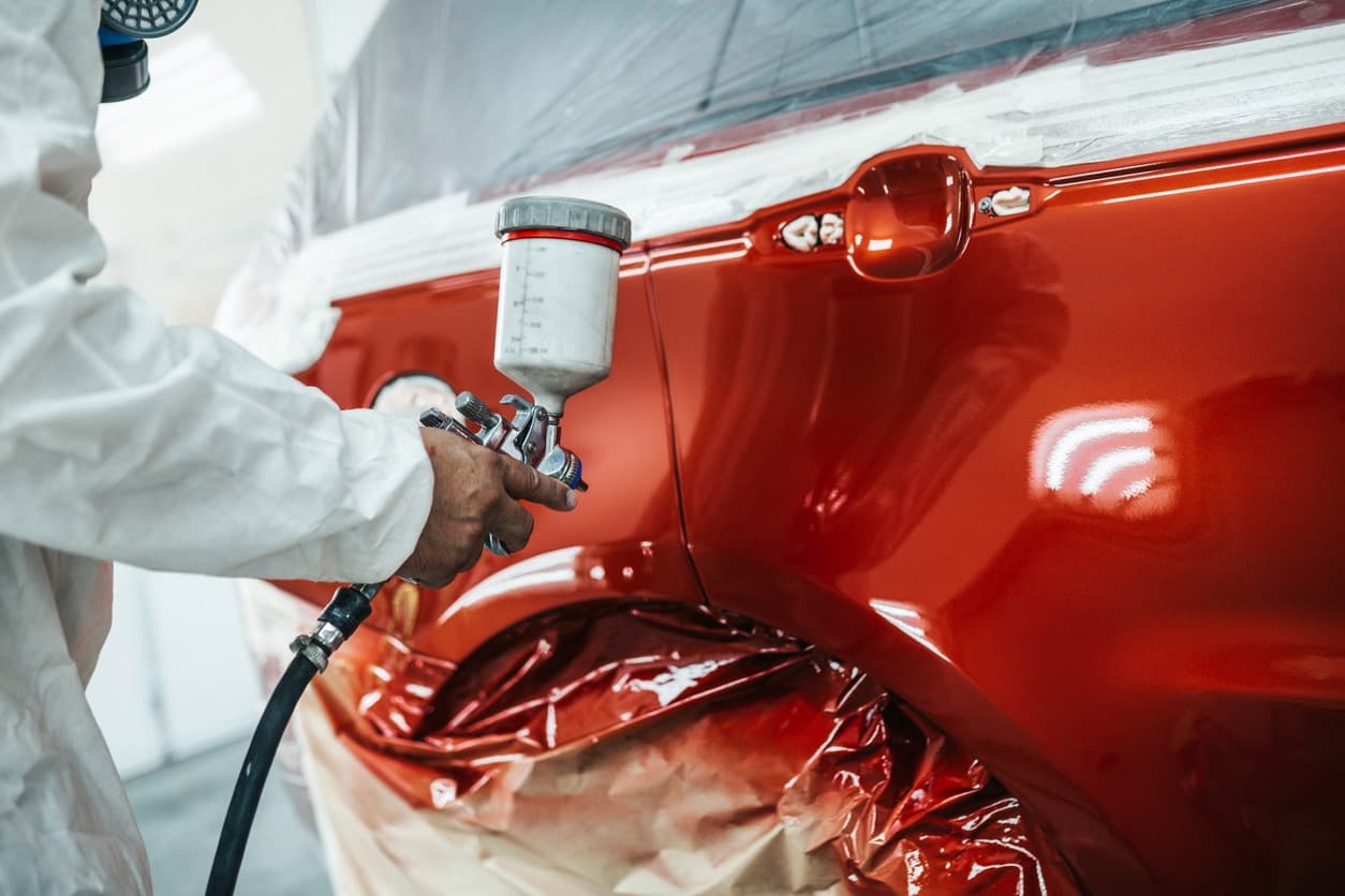A car being spray-painted in a paint booth