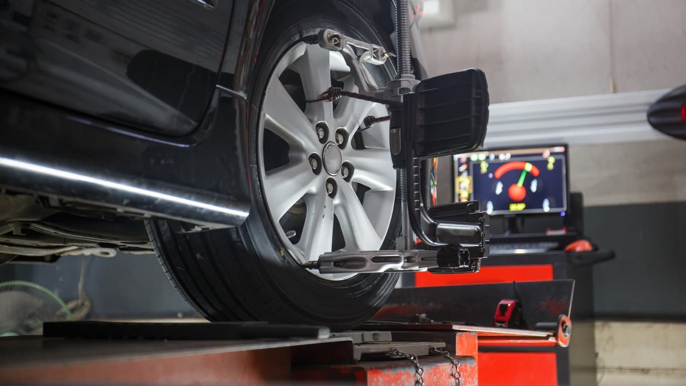 A car on a wheel-alignment stand with sensors on its wheels
